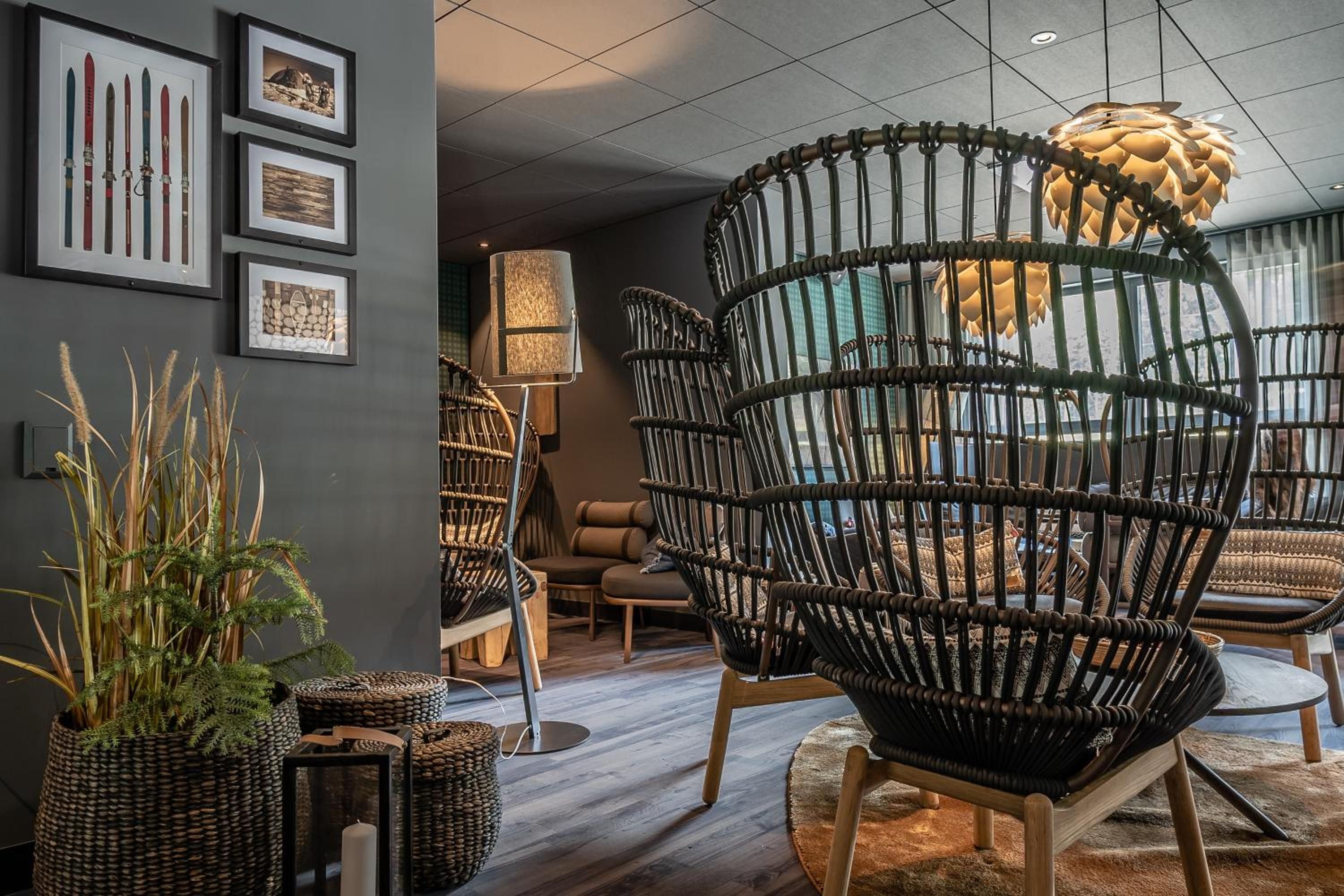 Un intérieur moderne avec des chaises en osier, un lampadaire et des tableaux encadrés accrochés au mur.