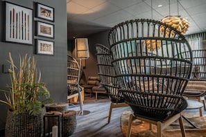 Un intérieur moderne avec des chaises en osier, un lampadaire et des tableaux encadrés accrochés au mur.