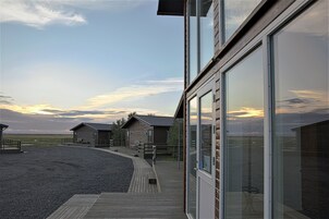 Un edificio moderno con grandes ventanales, una terraza de madera y vistas del paisaje.