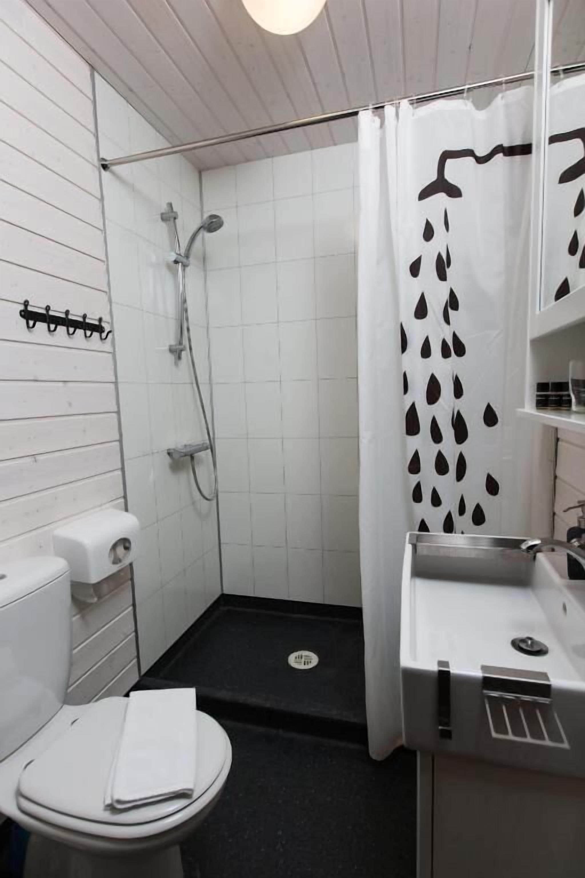 Casa de banho pequena e compacta com sanita, lavatório e chuveiro.