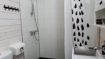 Casa de banho pequena e compacta com sanita, lavatório e chuveiro.