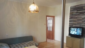 A living room with a sofa, a coffee table, a television, and a wooden floor. - Apartamenty Gdańsk - Apartament Ogarna (Gdansk)