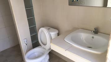 A bathroom with a toilet, sink, and mirror.