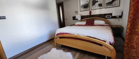 Ein Schlafzimmer mit einem hölzernen Bett, flauschigen weißen Teppichen und drei Wandbildern mit Hirschmotiven.