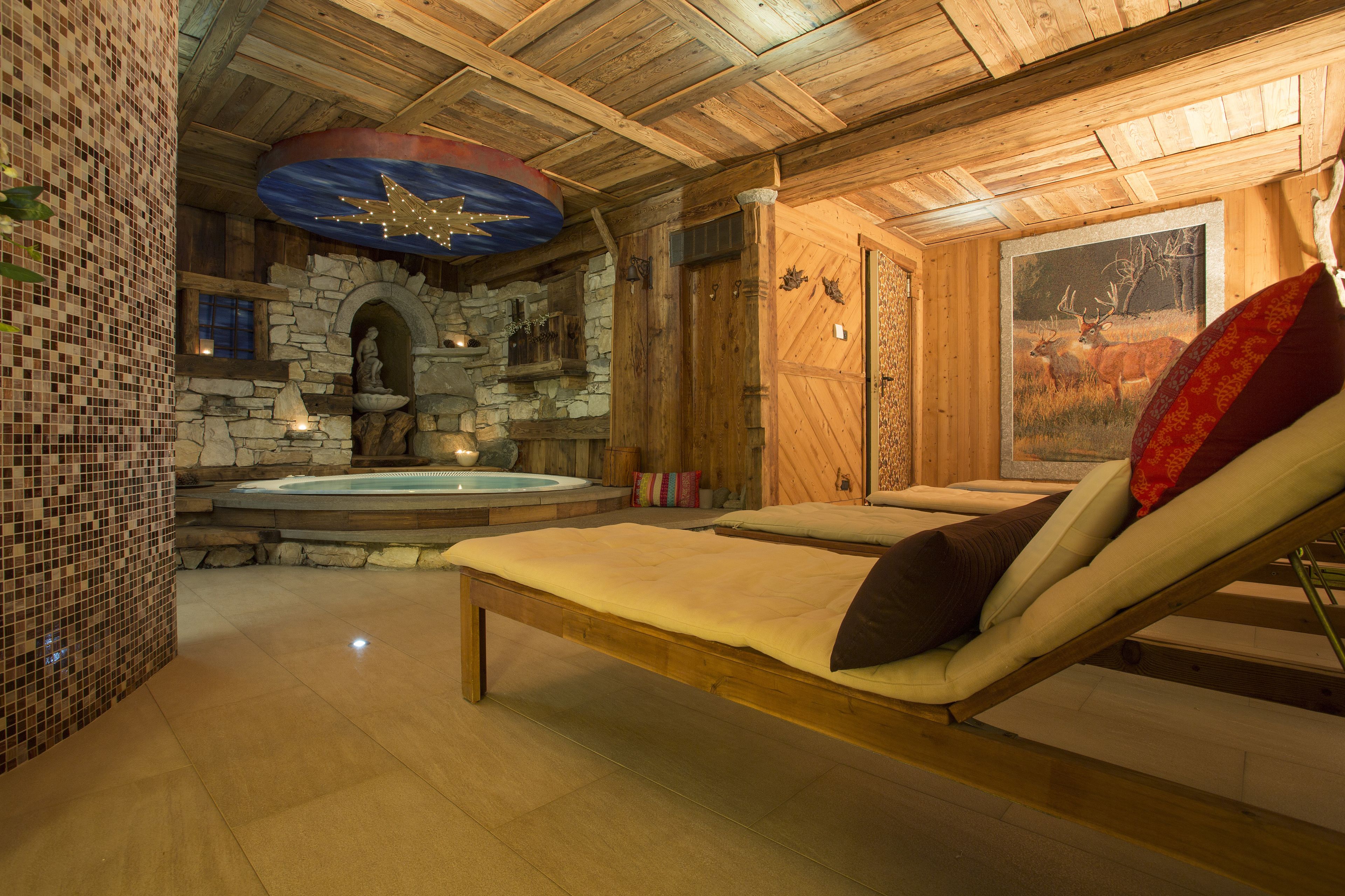 Een spa-ruimte met een stenen openhaard, een massagetafel en een schilderij van herten.