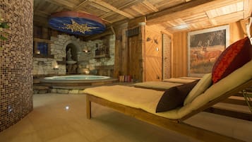 Une salle de spa dotée d’une cheminée en pierre, d’une table de massage et d’un tableau représentant des cerfs.