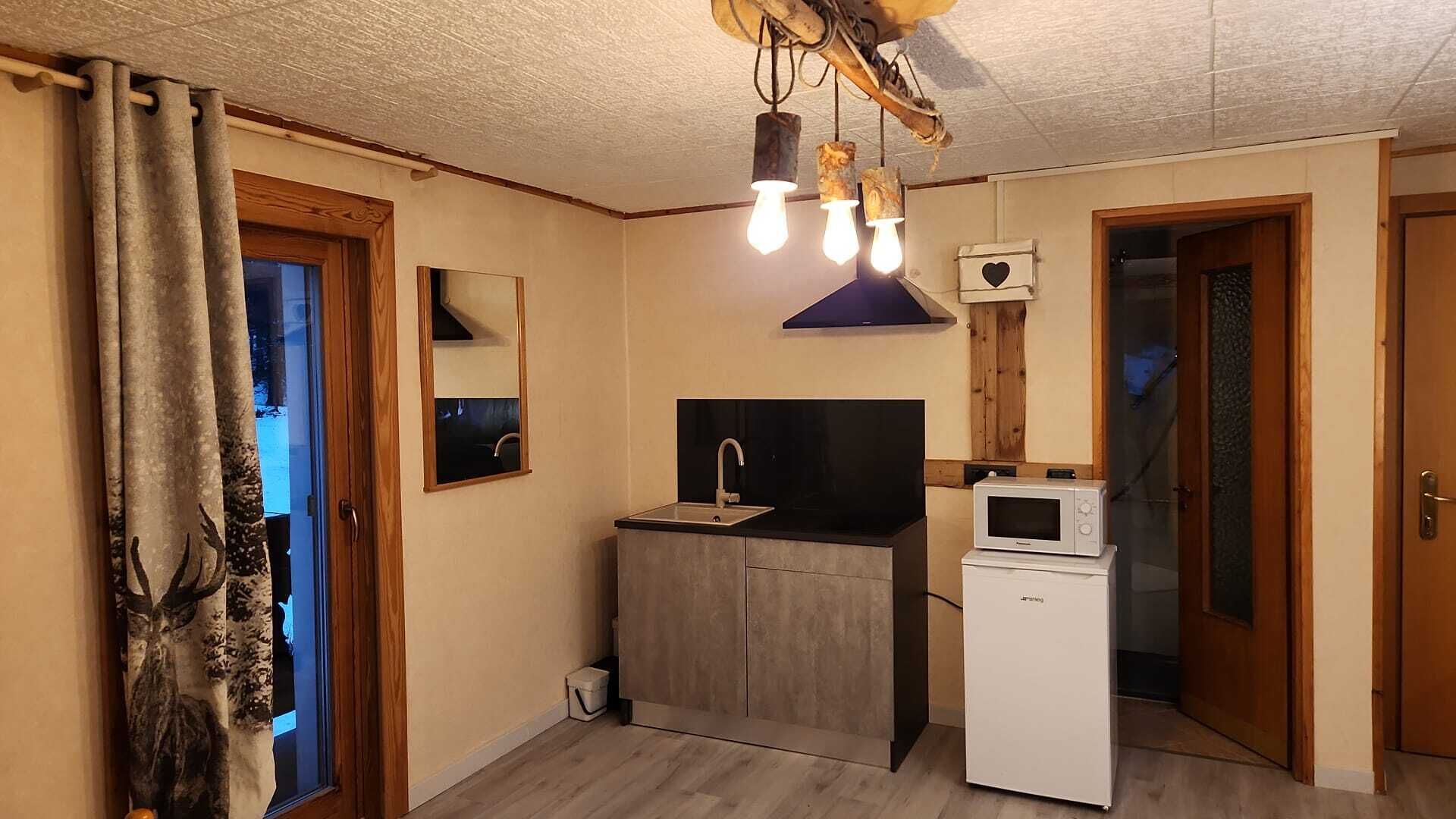 Een compacte keuken met een spoelbak, een magnetron en een plafondlamp.