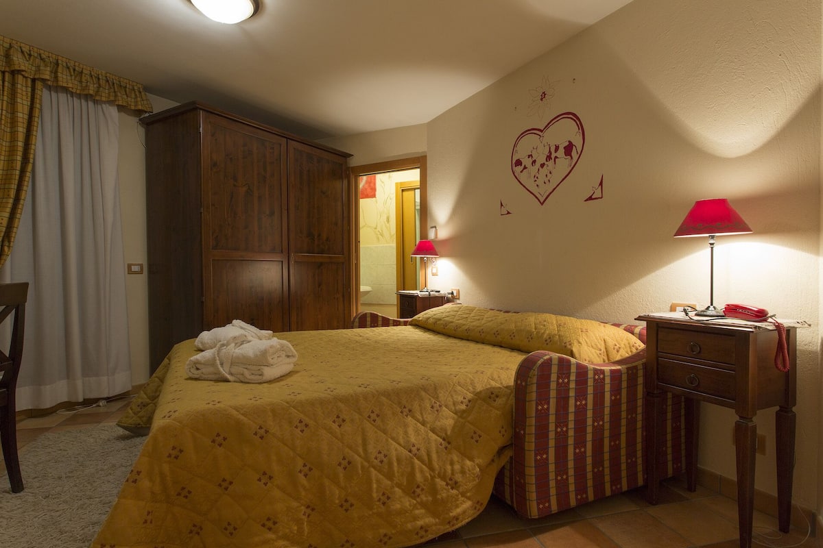 A bedroom with a bed, two bedside tables, a wardrobe, and a wall with a heart design.