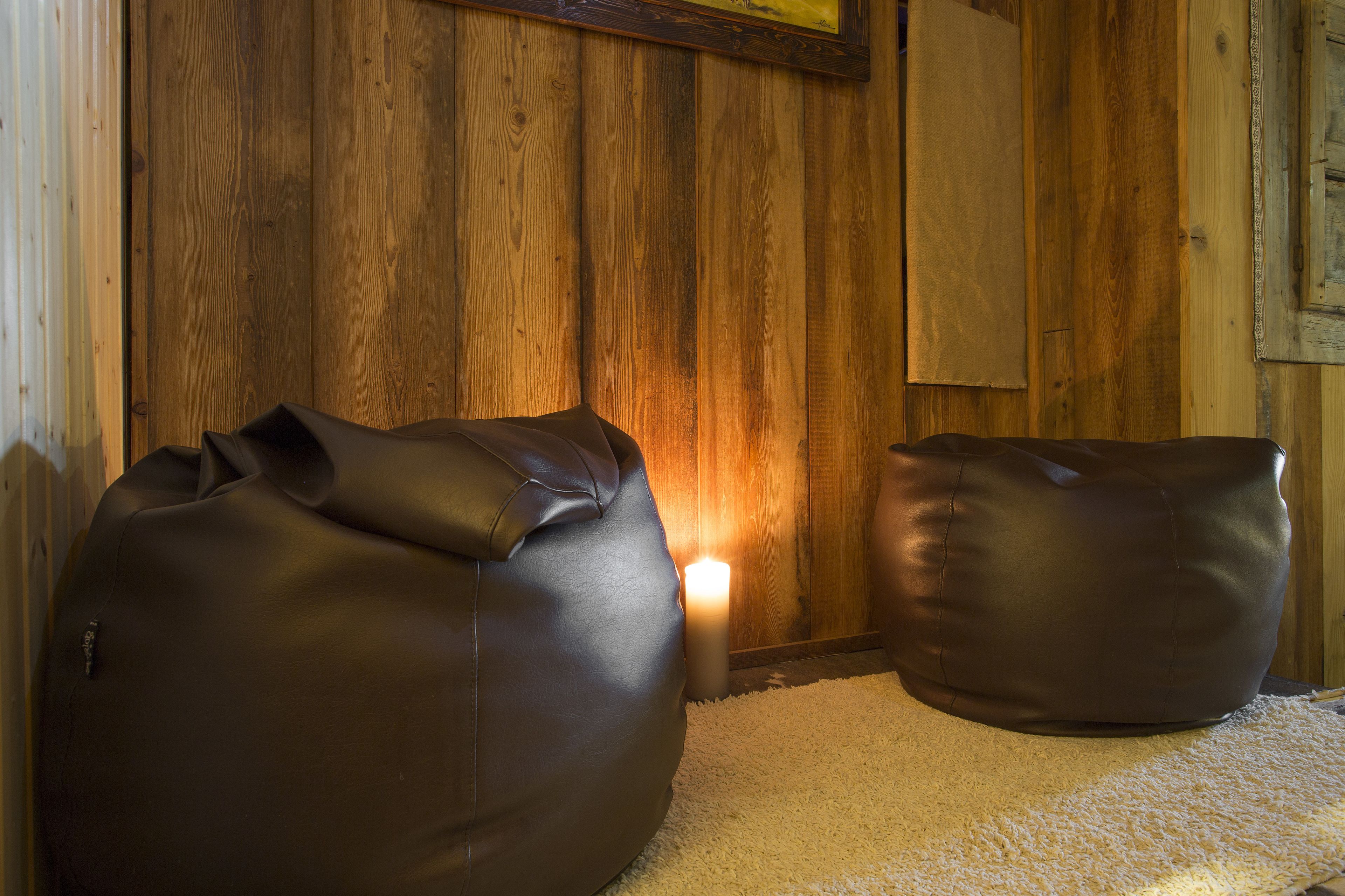 A room with wooden walls, a white carpet, and two dark-colored bean bags.