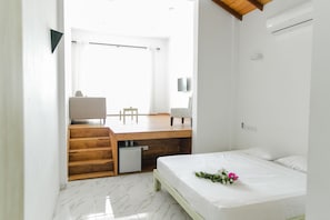 Quarto minimalista com cama, escrivaninha e cadeira.