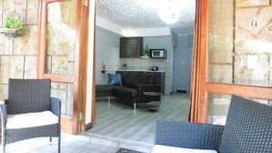 A room with a wooden door labeled "WILDEBEEST ROOM," wicker furniture, a microwave, and a small kitchen area. - Bushmans Rock Country Lodge (Roodeplaat)