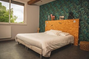 A bedroom with a bed, a window, a radiator, and a wall with a floral pattern.