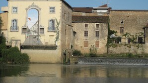 A historic building with a central archway, a stone facade, and a small water feature in front. - Le Jardin de la Reyssouze (Gorrevod)