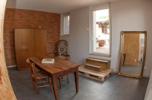A room with a wooden dining table, chairs, a wooden wardrobe, a window, and a mirror. - Le Jardin de la Reyssouze (Gorrevod)