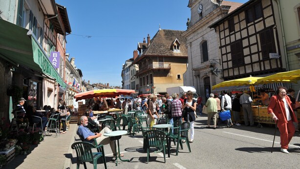 A bustling outdoor café area with tables and chairs, surrounded by buildings with historical architecture. - Le Jardin de la Reyssouze (Gorrevod)
