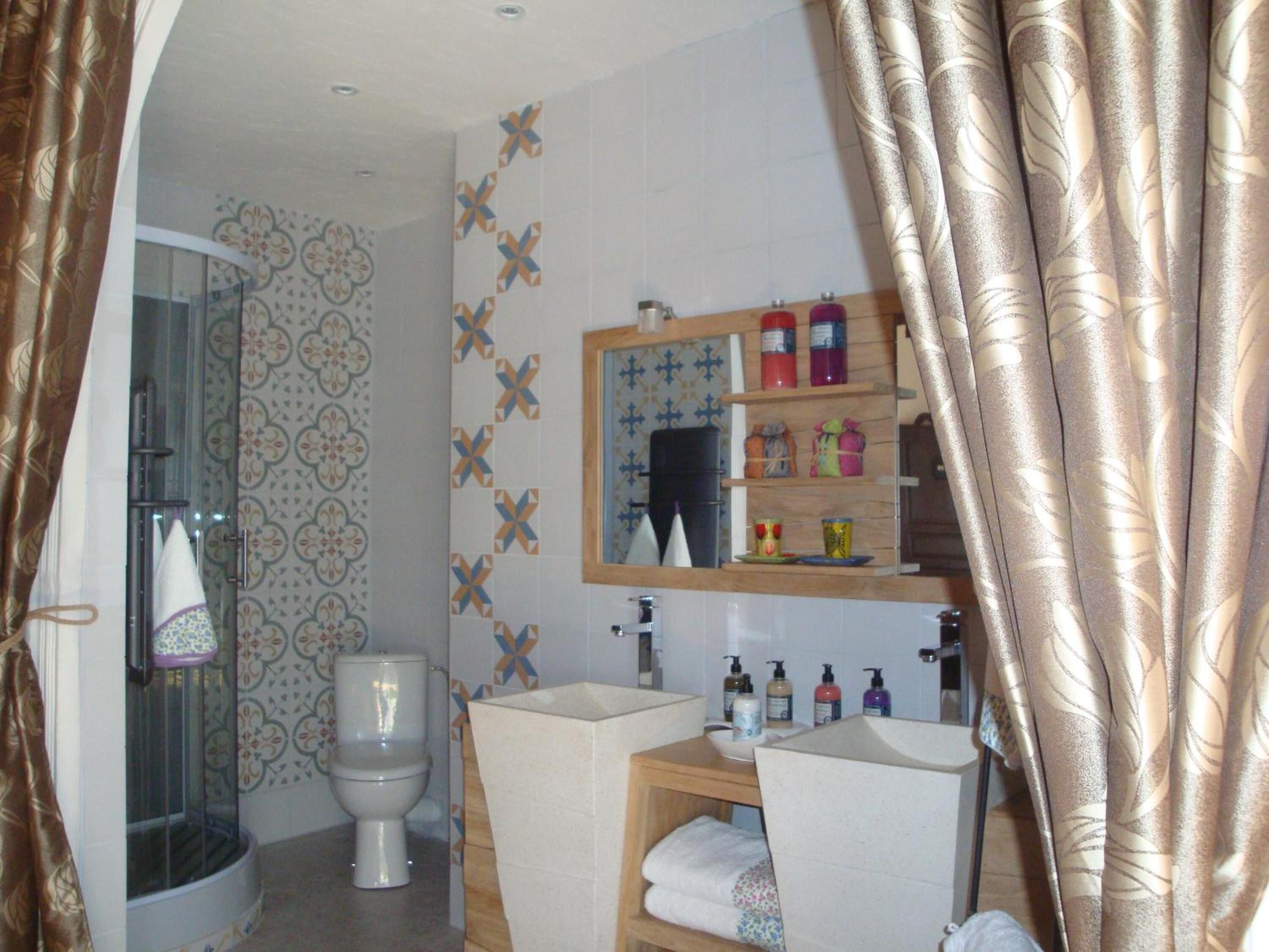 A bathroom with a toilet, shower, sink, and mirror.