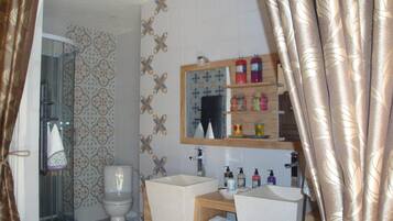 A bathroom with a toilet, shower, sink, and mirror.