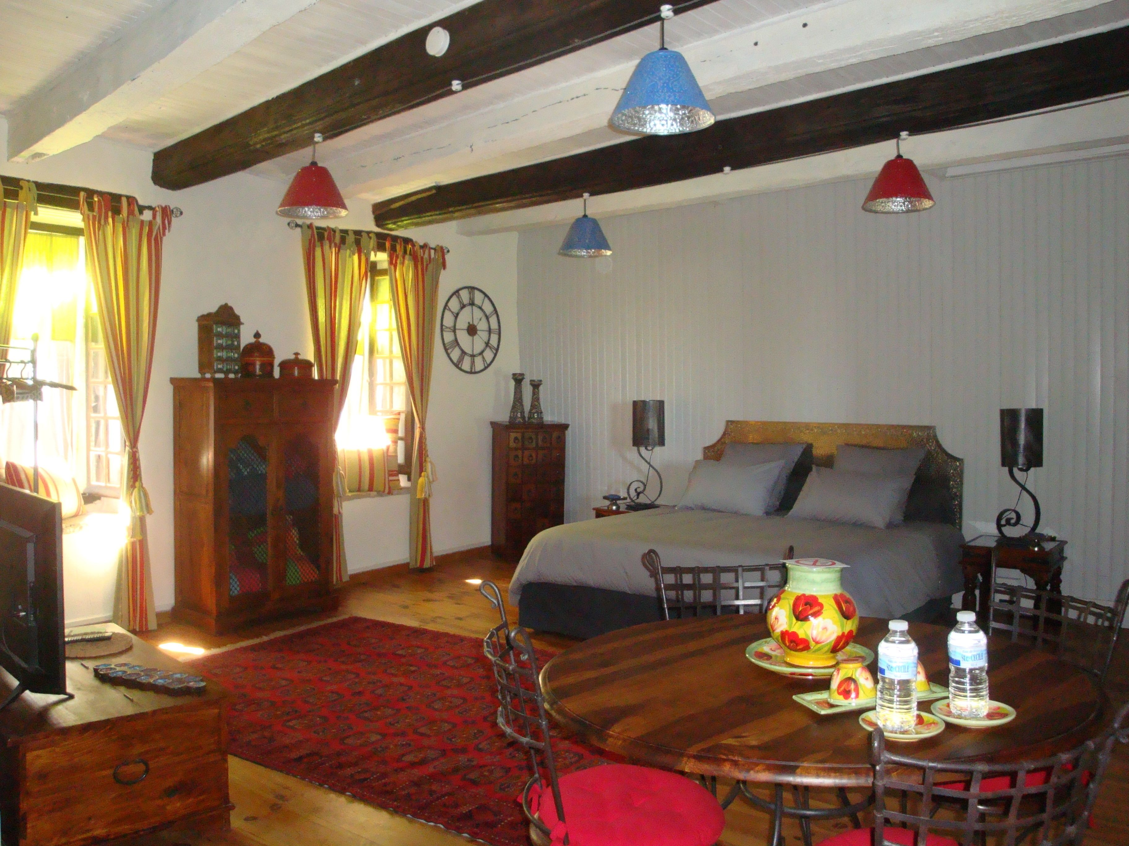 Una habitación de hotel con cama, cómoda de madera, mesa redonda con sillas y alfombra roja.