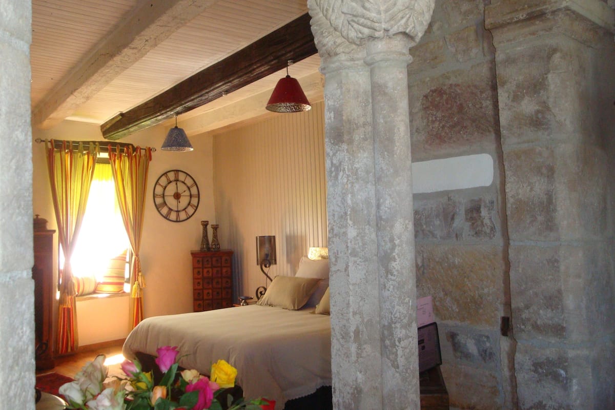 Ein Schlafzimmer mit Bett, einer Uhr und einem fenster mit Vorhängen.