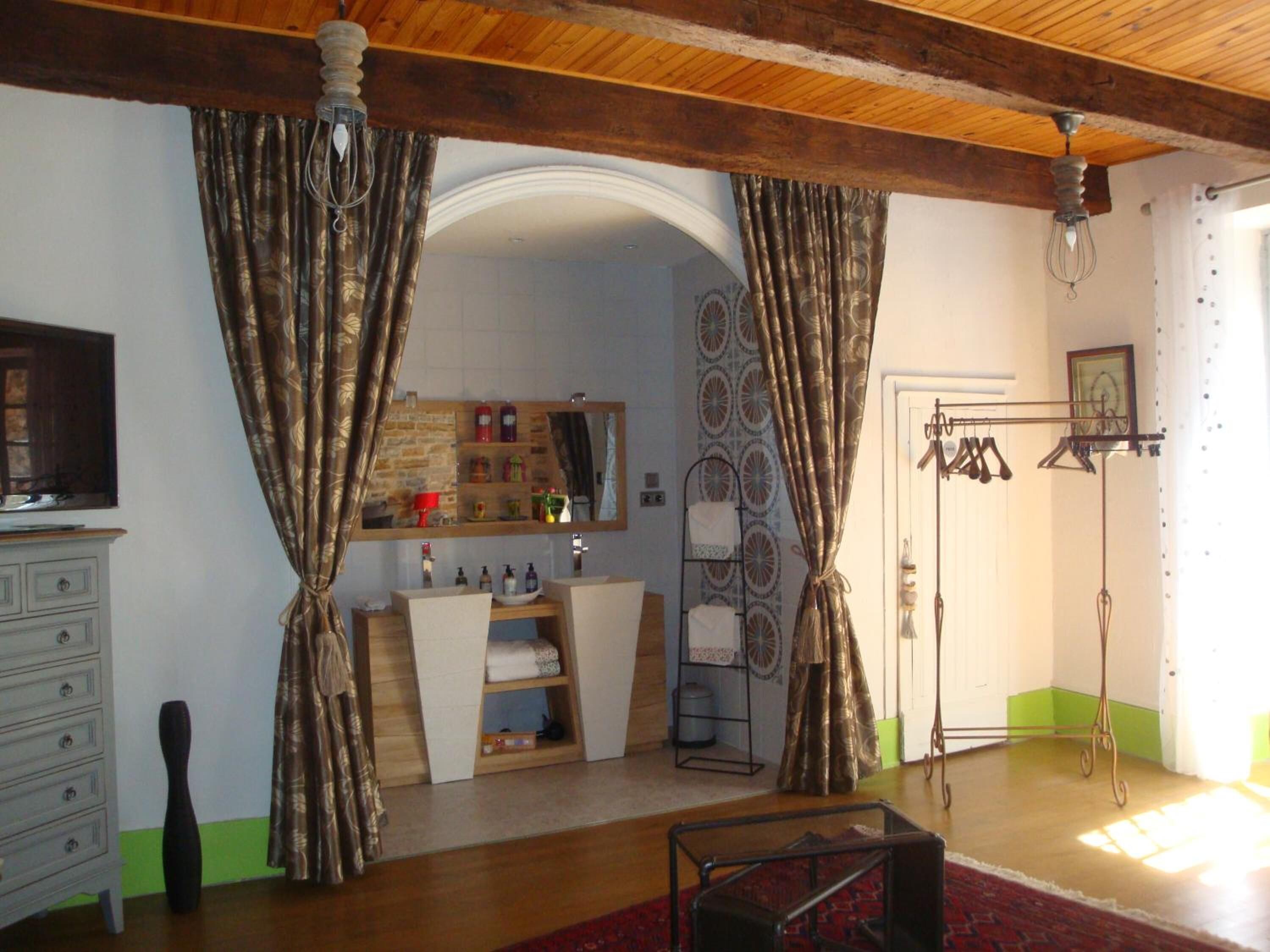 Una sala de estar con techo de madera, un televisor, un espejo, un aparador y un tapiz estampado.