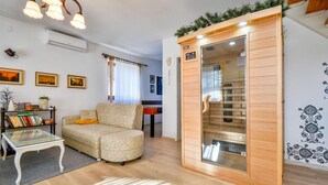 Ein gemütliches Wohnzimmer mit einer Couch, einem Glastisch und einem Holzschrank mit Sauna.