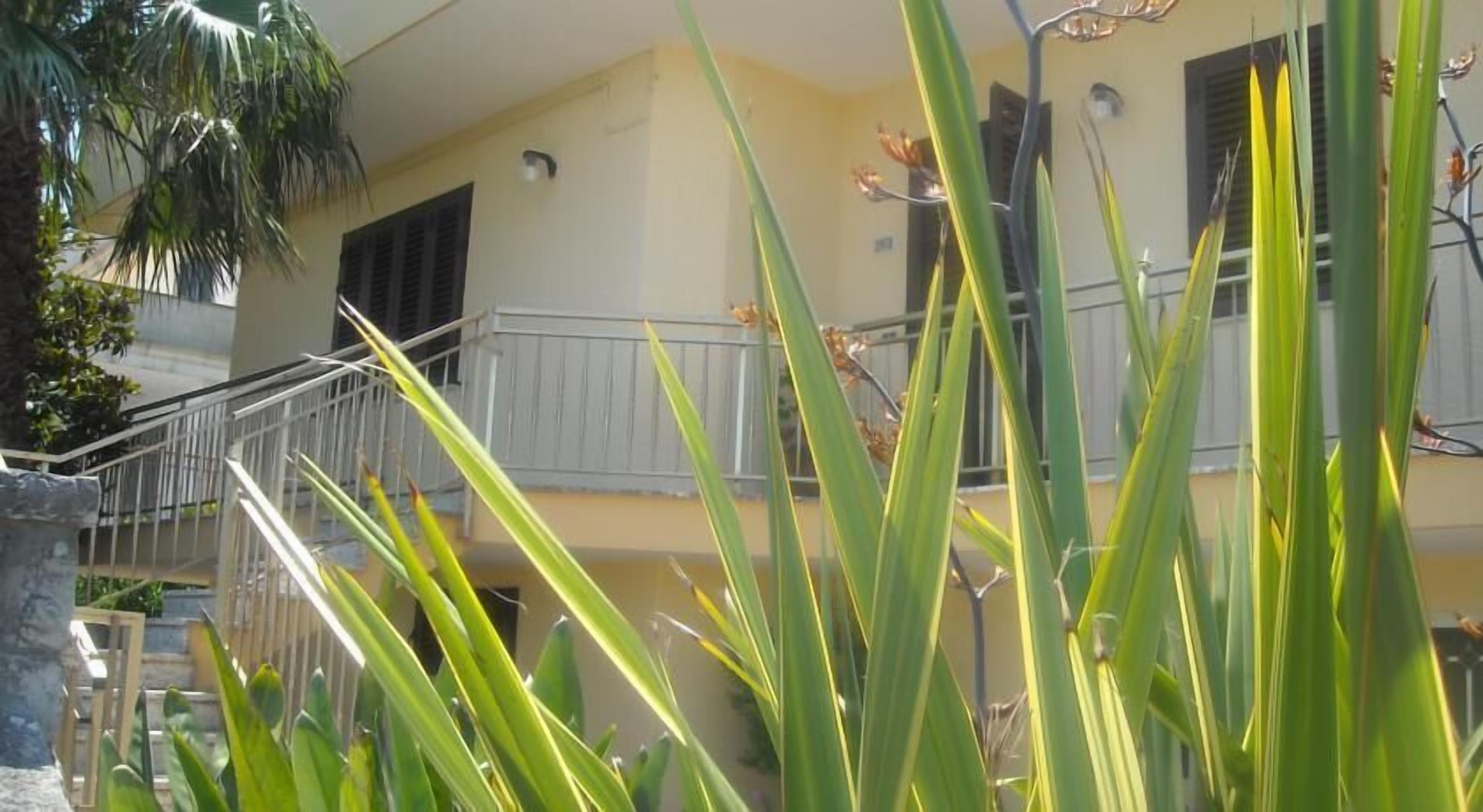 A building with a balcony, surrounded by greenery.