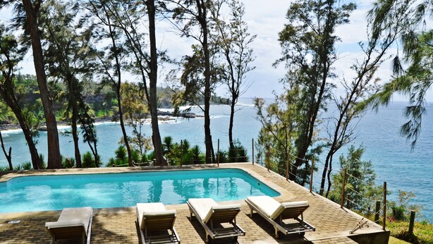 A pool with lounge chairs and a view of the ocean. - Andrea Lodges (Riviere des Anguilles)