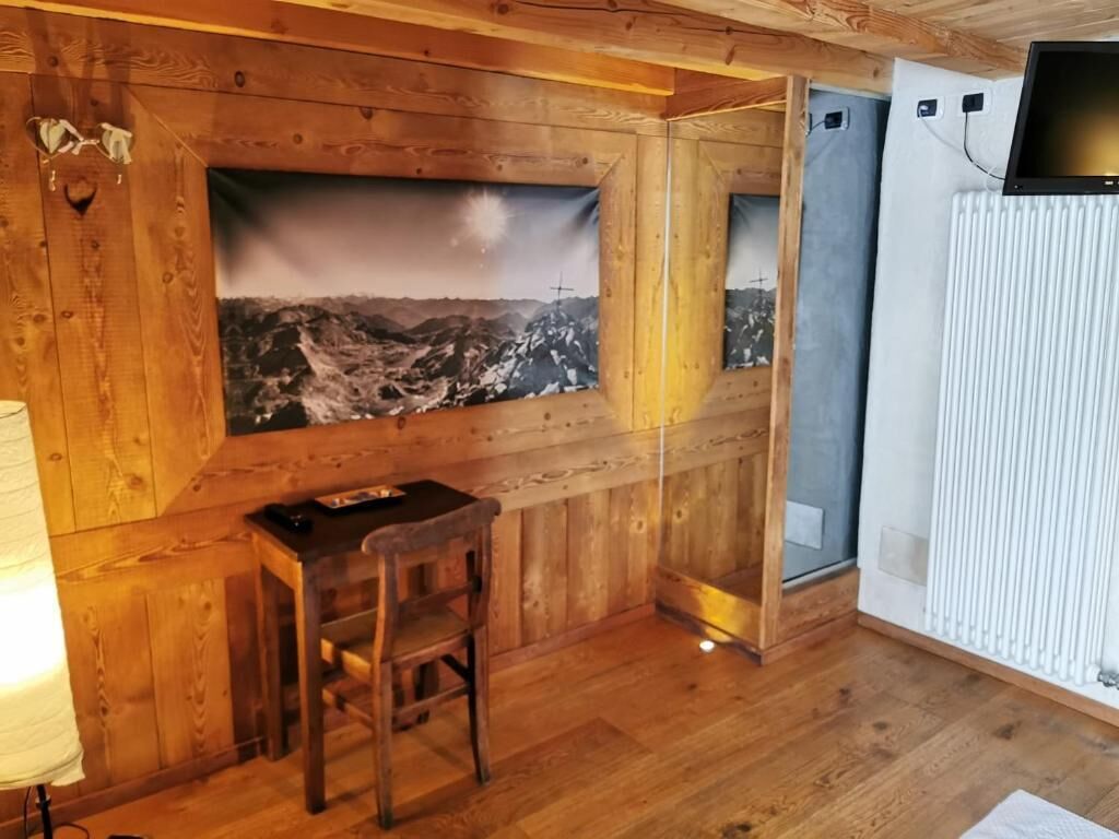 Une pièce de style cabane en bois, comprenant un bureau, une chaise et un grand tableau représentant un paysage de montagne.