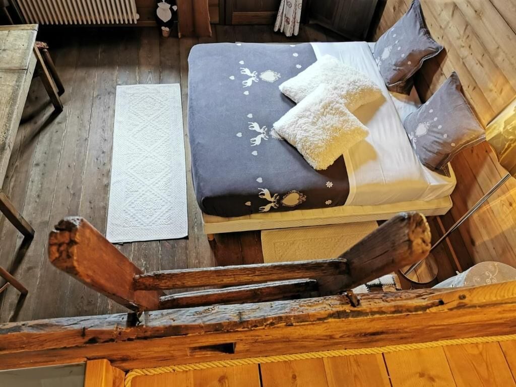 A wooden cabin-style room with a bed, pillows, and a white rug.