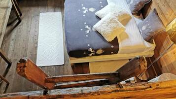 A wooden cabin-style room with a bed, pillows, and a white rug.