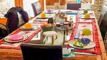 Un comedor con una larga mesa de madera dispuesta para una comida, rodeado de sillas.