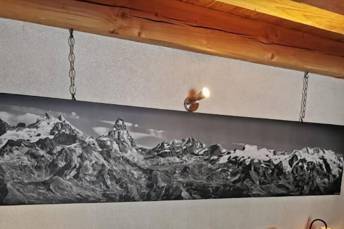 A bedroom with a bed, two pillows with deer designs, a painting of mountains, and a wooden headboard.
