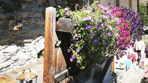 Un rústico edificio de piedra con vigas de madera y una jardinera llena de flores moradas.