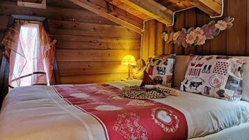 Un dormitorio de cabaña de madera con cama, almohadas y una mesita de noche con lámpara.
