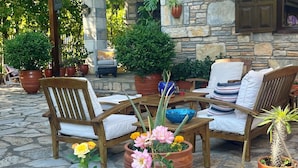 An outdoor seating area with stone walls, potted plants, and a covered patio. - Kamarca House Hotel (Ortaca)