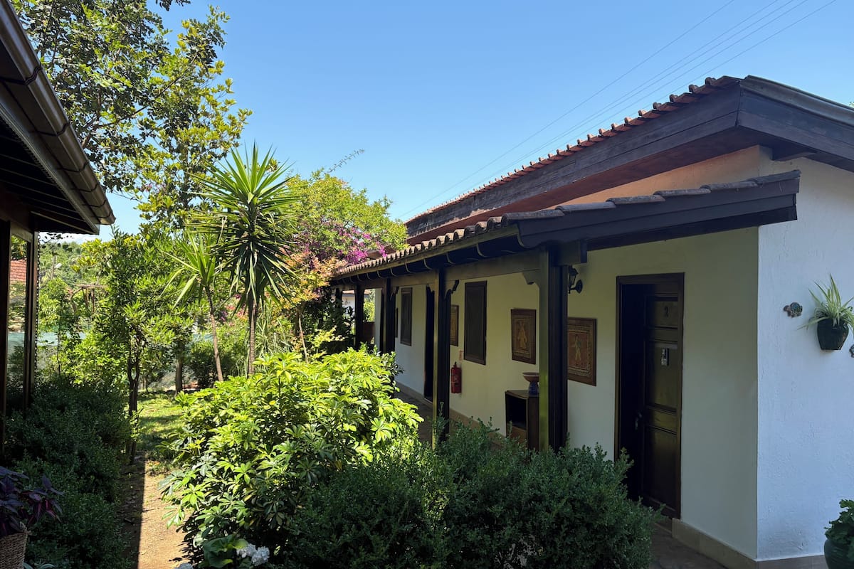 A traditional building with a tiled roof, a covered porch, and a garden with various plants and a palm tree.