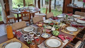 A dining area with multiple tables set for a meal, surrounded by wicker chairs and a view of a garden. - Kamarca House Hotel (Ortaca)