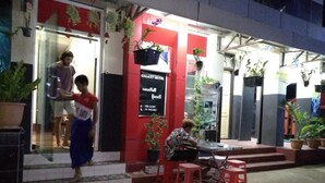 A Galaxy Motel with a red exterior, a signboard with contact numbers, and potted plants. - Galaxy Motel Hpa An (Hpa-An)