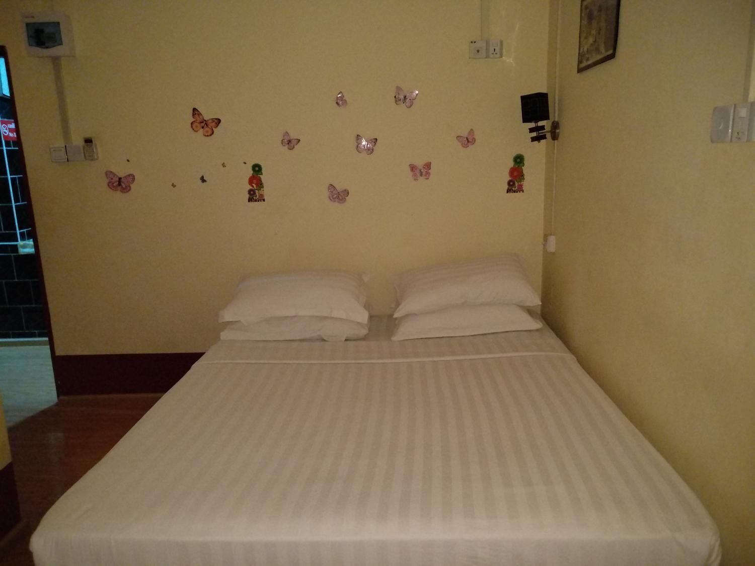 A room with a bed, two pillows, and butterfly wall decals.