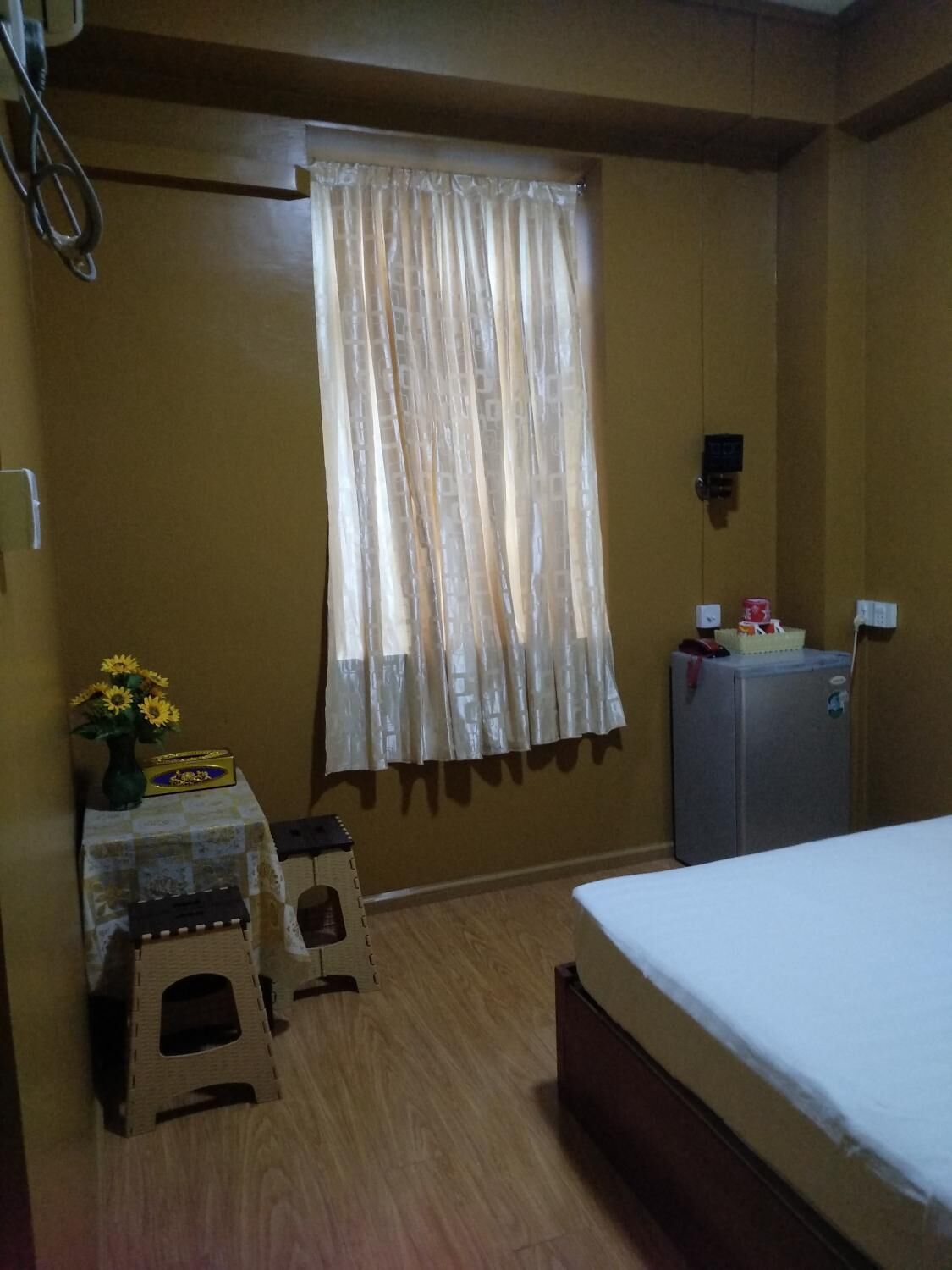 Una habitación pequeña y acogedora con una cama, un escritorio con silla, un radiador y una ventana con cortinas.