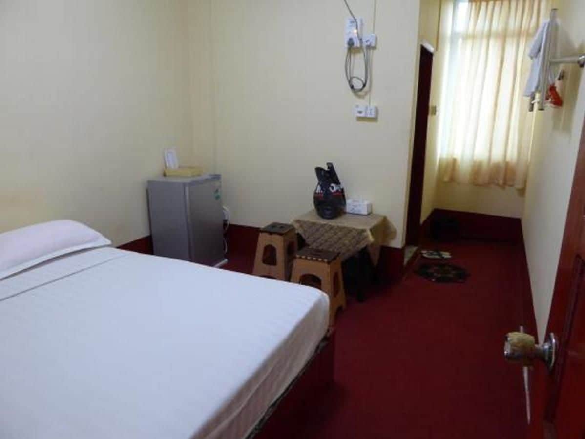 Una habitación de hotel con cama, una mesita con una silla, un escritorio y un armario.