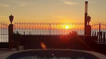 Una piscina con vista al atardecer, rodeada por una valla y faroles.