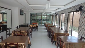 A restaurant with long tables covered in gold tablecloths, wooden chairs, and a view through large windows. - Porto Palace Pousada (Ipojuca)