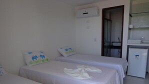 A hotel room with three beds, a kitchenette, and a bathroom visible through an open door. - Porto Palace Pousada (Ipojuca)