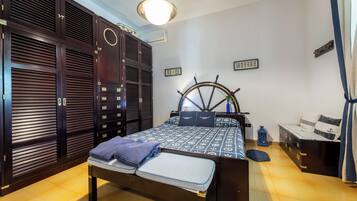 A bedroom with a bed, wardrobe, and a ship's wheel decoration.