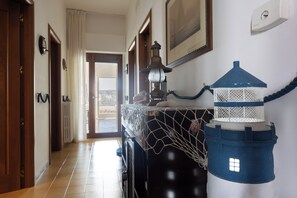 Un passadís amb vista a l'exterior, una taula amb funda de xarxa i un llum blau decoratiu.
