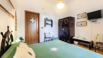 A bedroom with a bed, a wardrobe, a television, and a door with a life preserver.