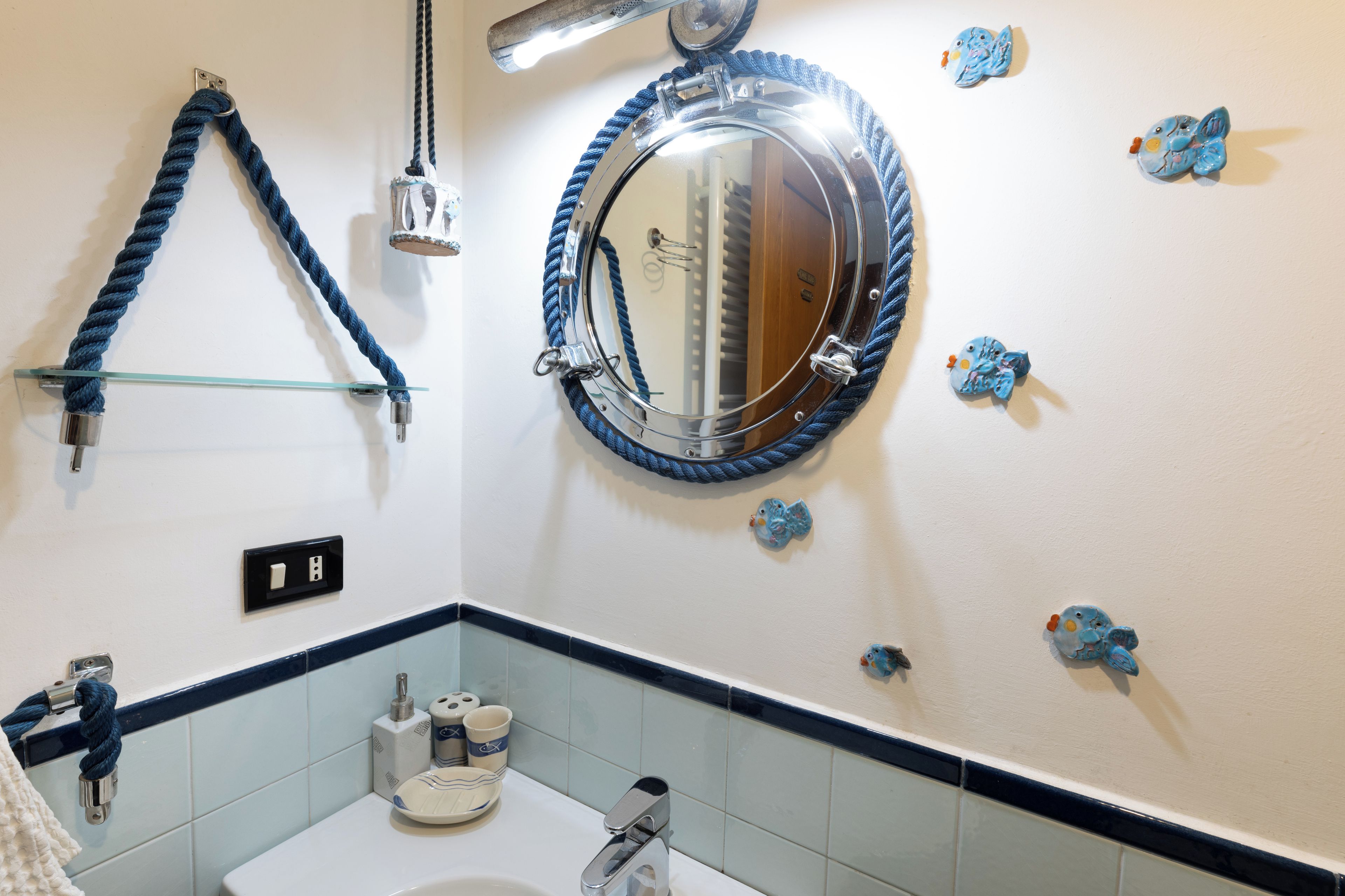 A bathroom with a round mirror, a towel rack, and decorative wall tiles.