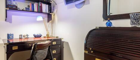 Una sala studio con scrivania, sedia, libreria, lampada e un grande specchio.