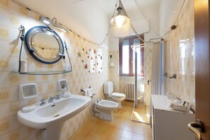 Une salle de bain équipée d’un lavabo, de toilettes, d’un bidet et d’un espace douche.